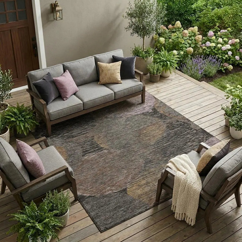 Gray outdoor sofa set on wood deck with multicolored round rug, accented by potted plants and decorative pillows.