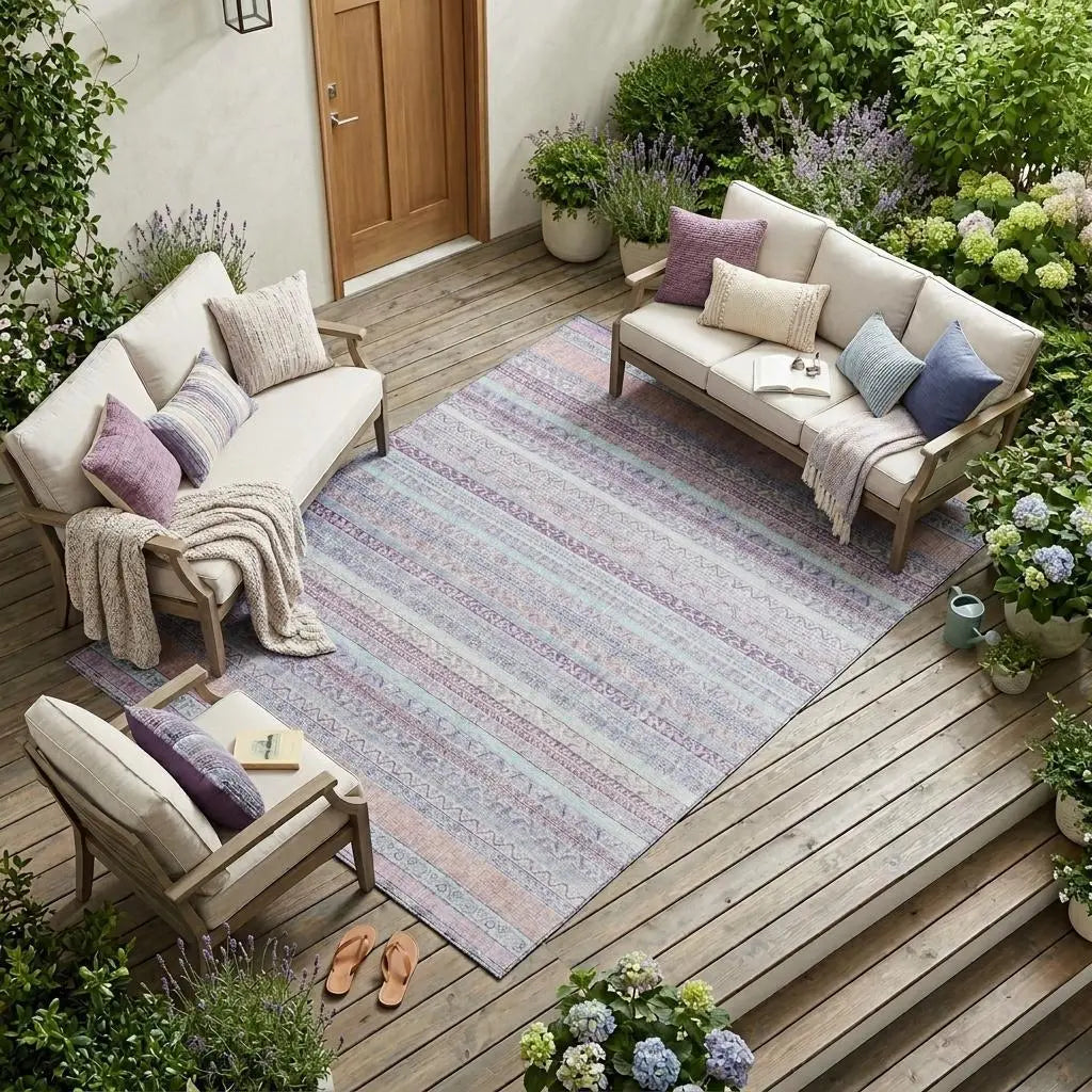 Cozy outdoor seating with beige sofas, lavender cushions, and a patterned area rug in pastel colors on a wooden deck.