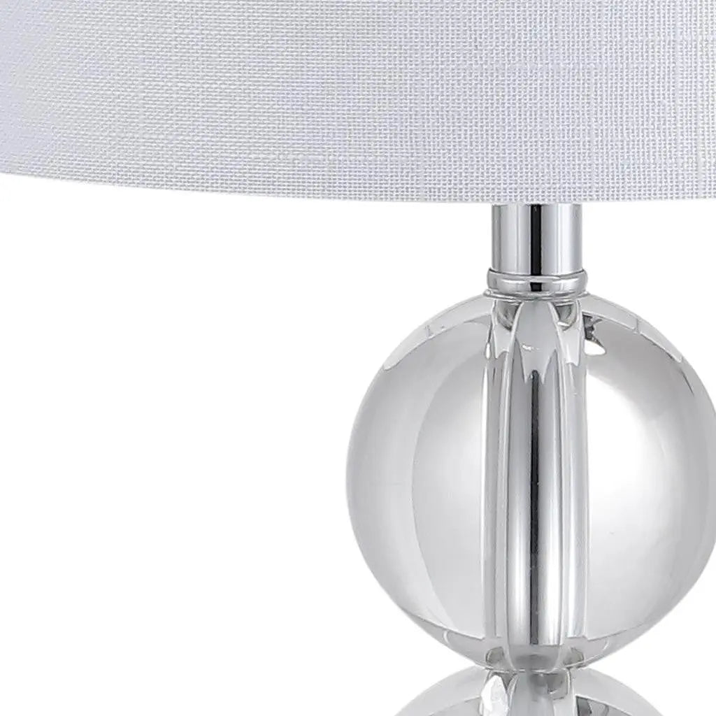 Clear glass table lamp with a modern round base and white fabric shade, perfect for contemporary decor.