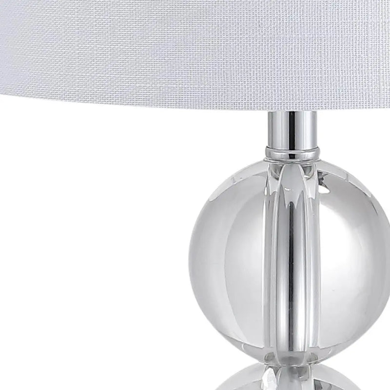 Clear glass table lamp with a modern round base and white fabric shade, perfect for contemporary decor.