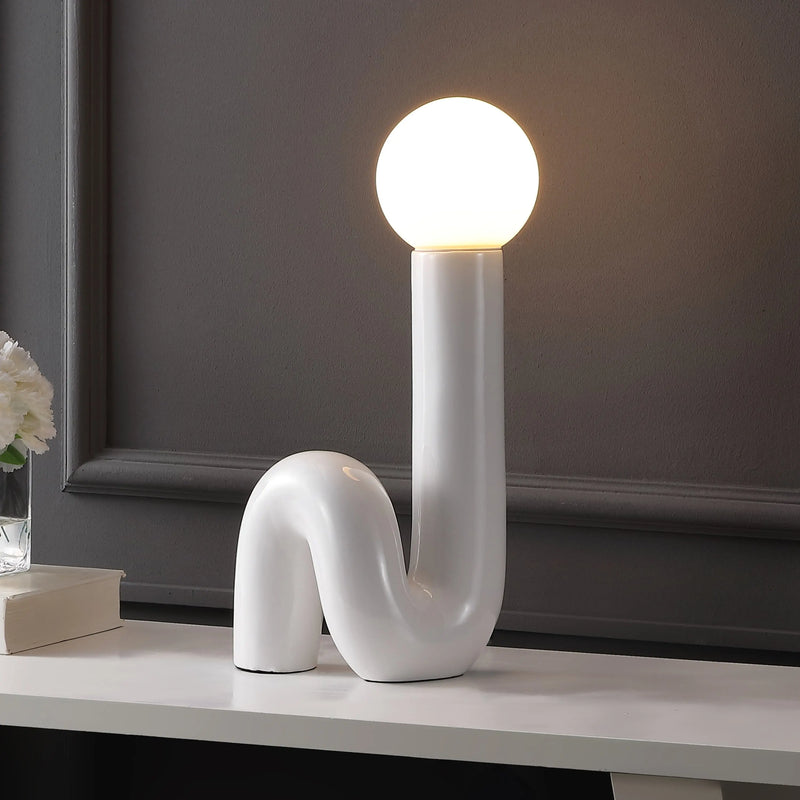 White ceramic wavy table lamp with a round frosted glass bulb, modern design for stylish home decor.
