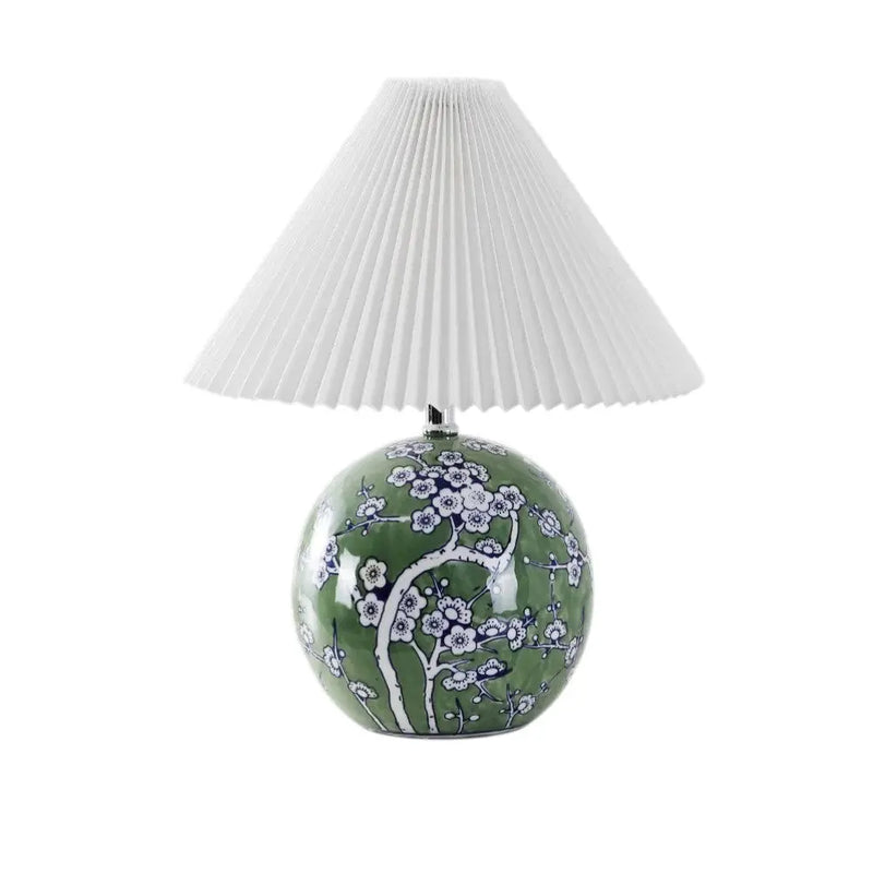 Green ceramic lamp with floral design and white pleated shade, perfect for a contemporary home decor.