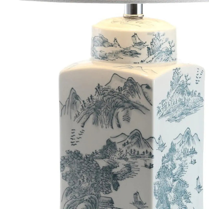Blue and white porcelain lamp with a scenic mountain design, featuring a coordinating fabric shade.