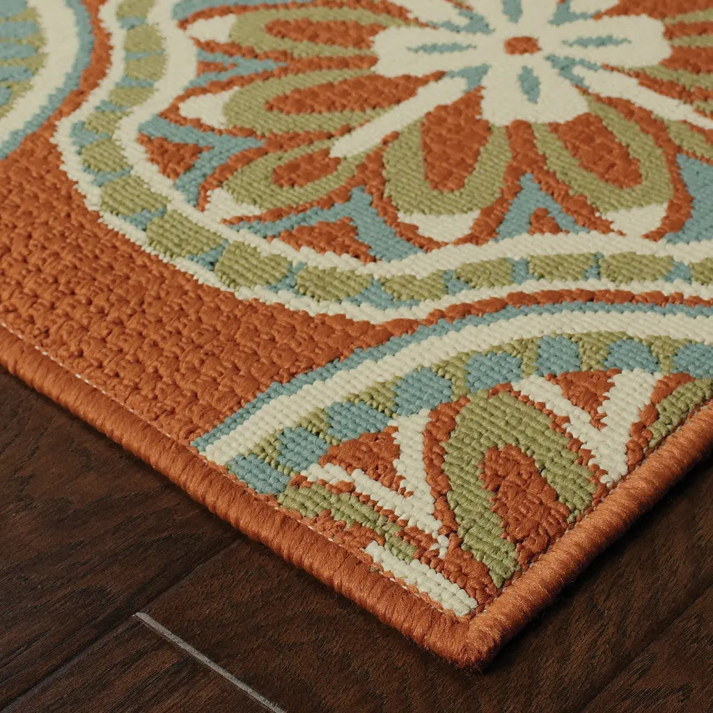Textured orange area rug with floral design in cream, green, and blue, perfect for vibrant home decor.