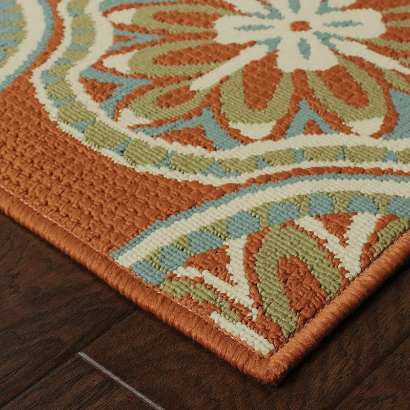 Textured orange area rug with floral design in cream, green, and blue, perfect for vibrant home decor.