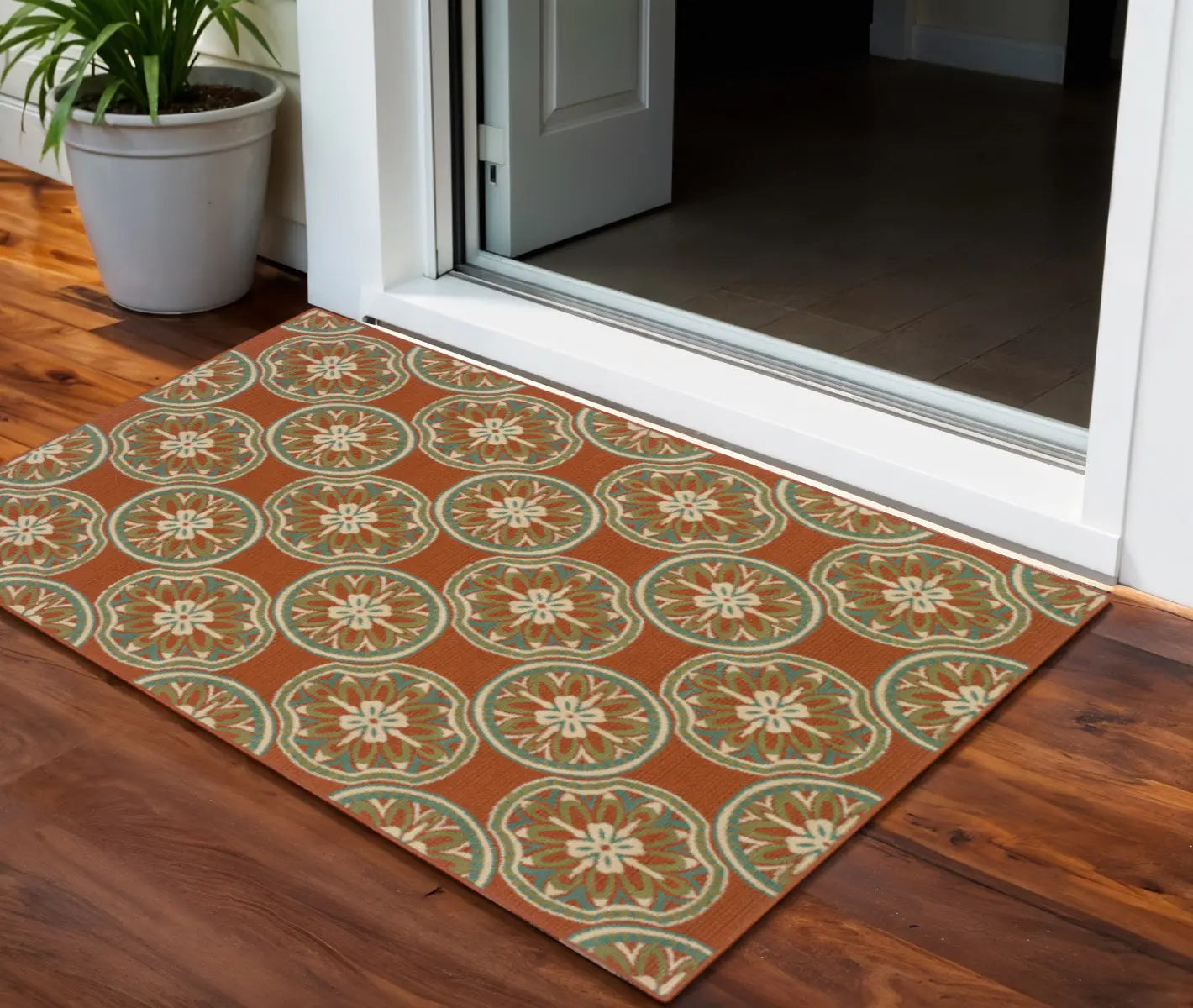 Orange floral patterned indoor/outdoor rug with intricate design, perfect for entryways and patios.
