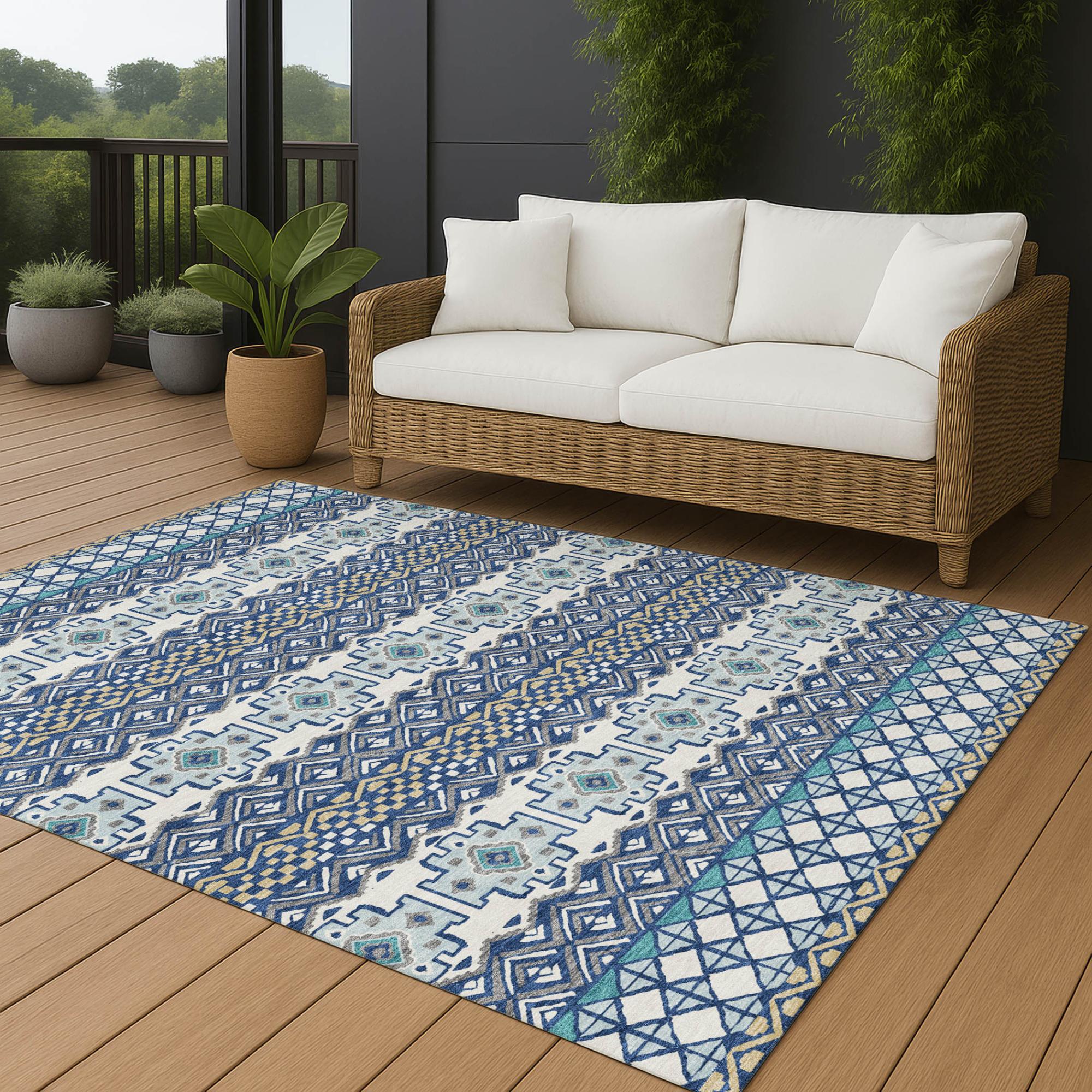 Blue and white patterned area rug on a wooden patio, paired with a comfortable white couch and greenery.
