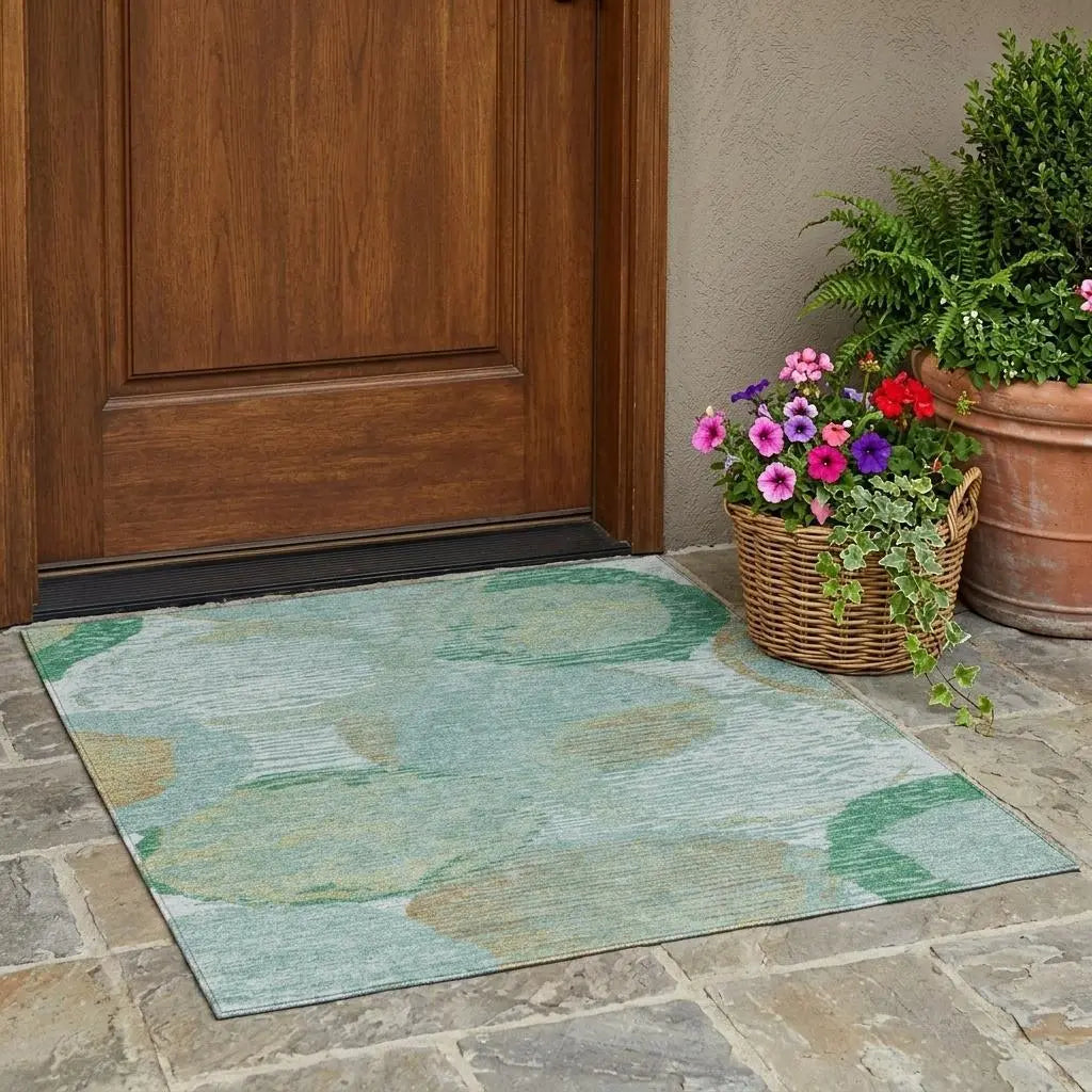 Teal outdoor area rug with green and beige floral design, perfect for entryways, paired with potted flowers.
