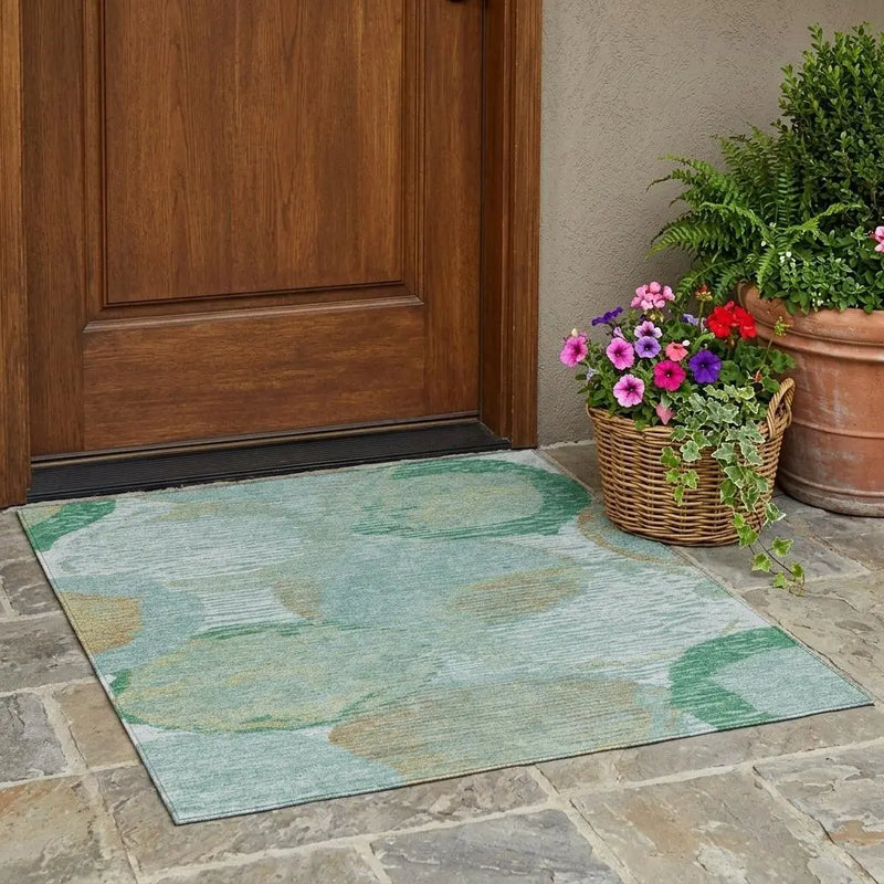 Teal outdoor area rug with green and beige floral design, perfect for entryways, paired with potted flowers.