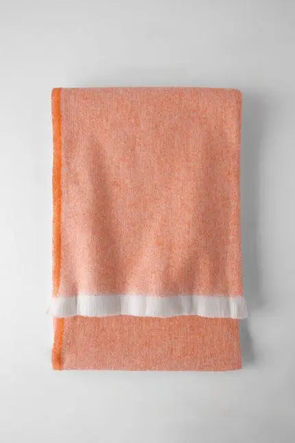 Soft orange woven blanket with white fringe trim, perfect for cozying up in style. Ideal for home decor or gifting.