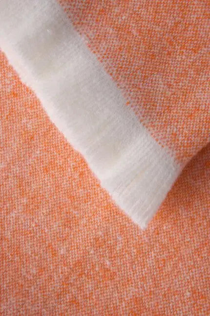 Soft orange melange cashmere fabric with a cozy white trim, ideal for stylish winter apparel.