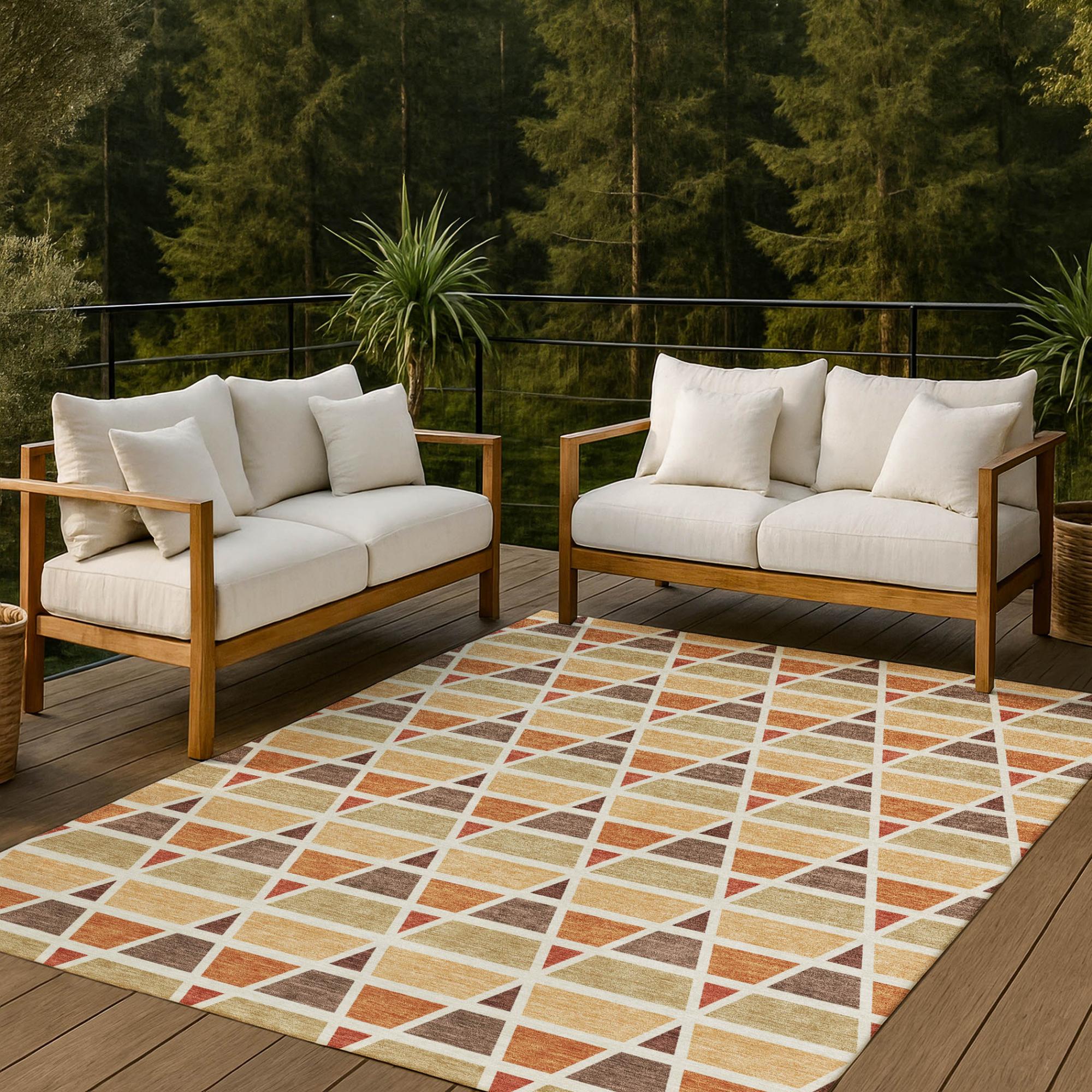 Geometric outdoor rug with orange, yellow, and brown tones, paired with a light beige sofa and wooden frame on a deck.