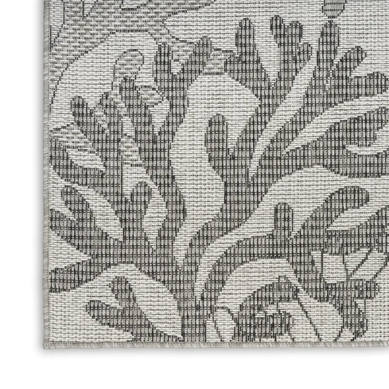 Gray woven area rug featuring a textured floral pattern in modern style. Ideal for contemporary home decor.