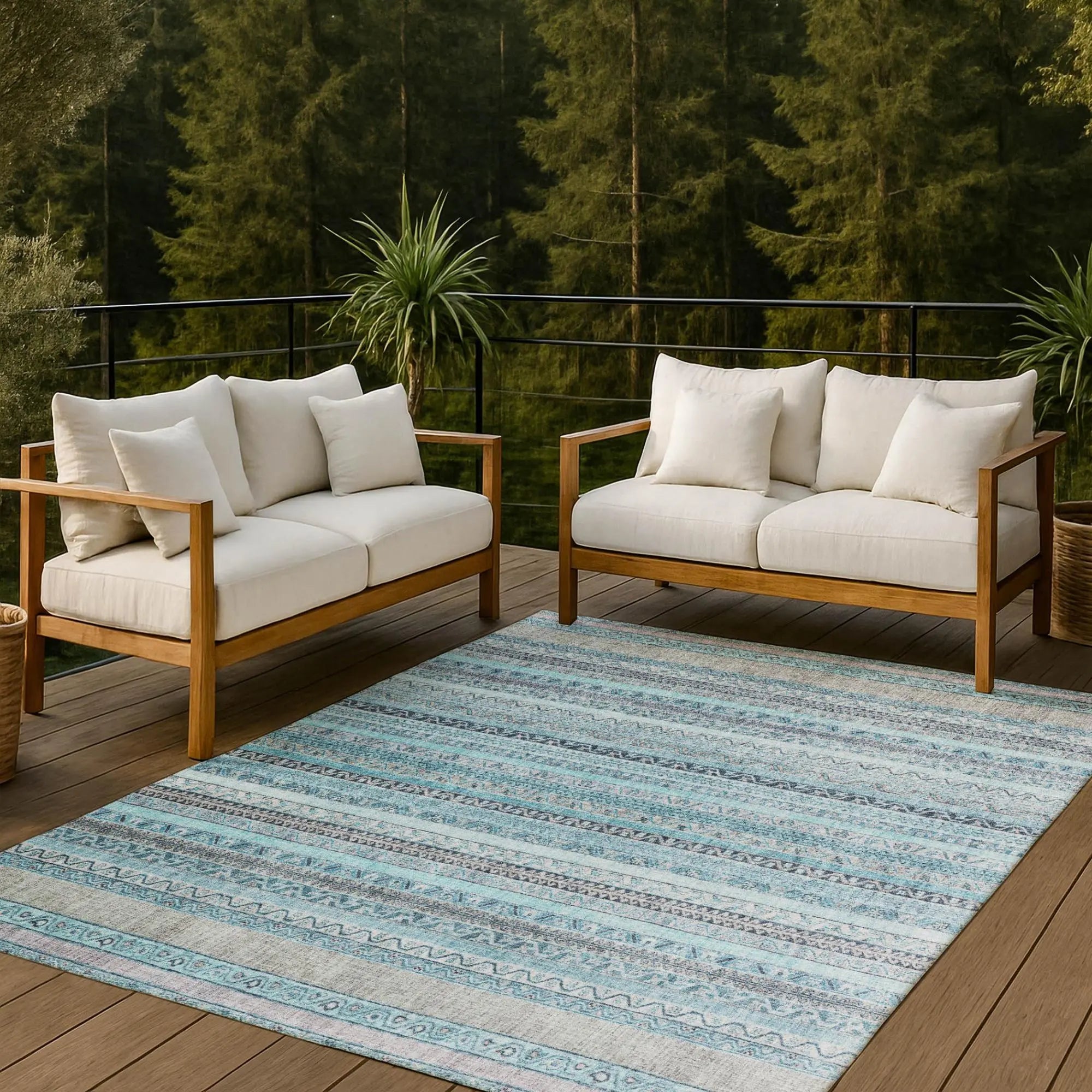 Light blue patterned area rug on a wooden deck, paired with cream outdoor sofas and a serene forest backdrop.