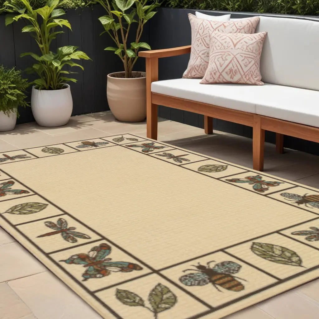 Beige outdoor rug with bee and leaf design, bordered in black, perfect for patios or garden seating areas.