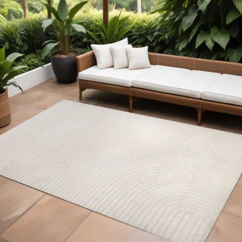 Neutral beige area rug with textured design, perfect for stylish outdoor or indoor spaces, paired with sleek wicker furniture.