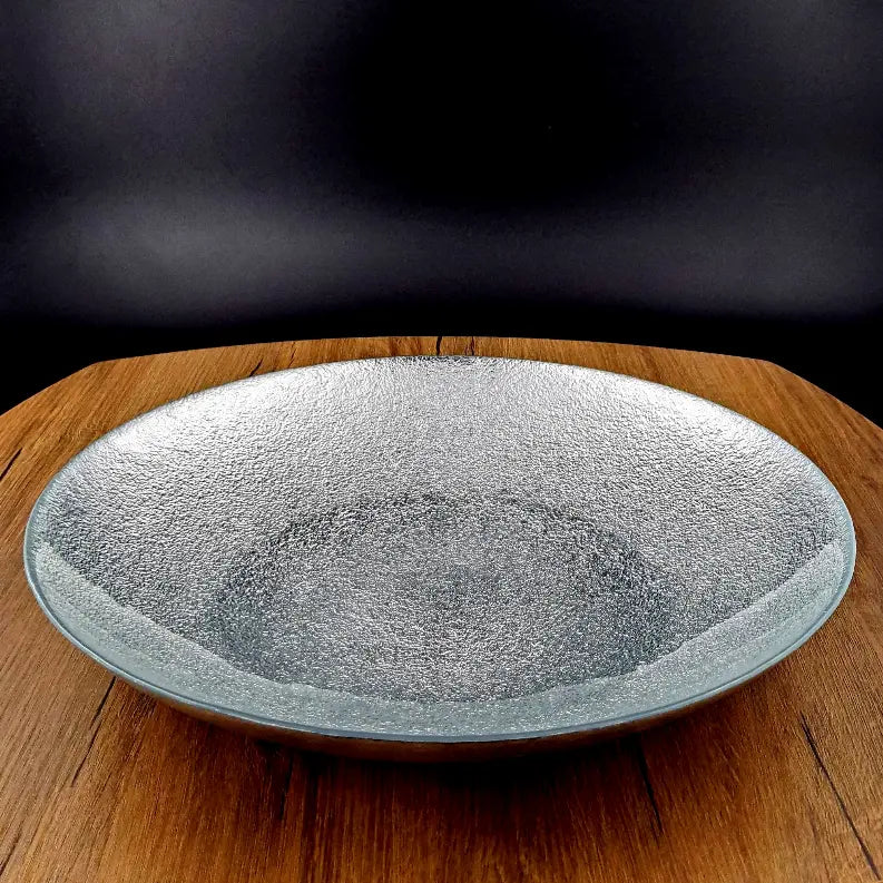 Textured clear glass serving bowl with a wide rim, perfect for salads or decor, resting on a wooden surface.