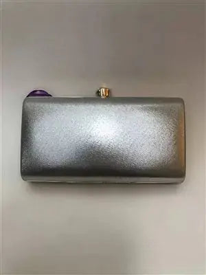 Silver metallic clutch with a purple gemstone clasp, elegant evening accessory for parties and formal events.