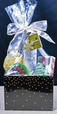 Holiday gift basket with festive soaps, yellow bath bomb, and shimmering gold polka dot box, wrapped in clear ribbon.