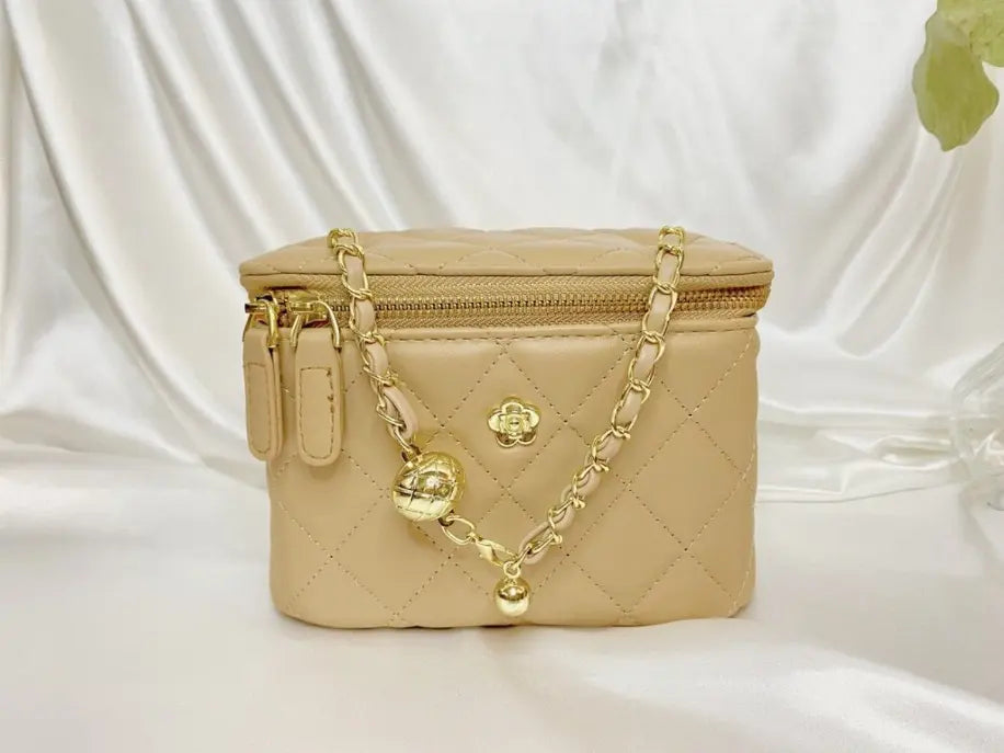 Beige quilted leather cosmetic bag with gold chain strap, featuring a gold charm for a chic, stylish look.