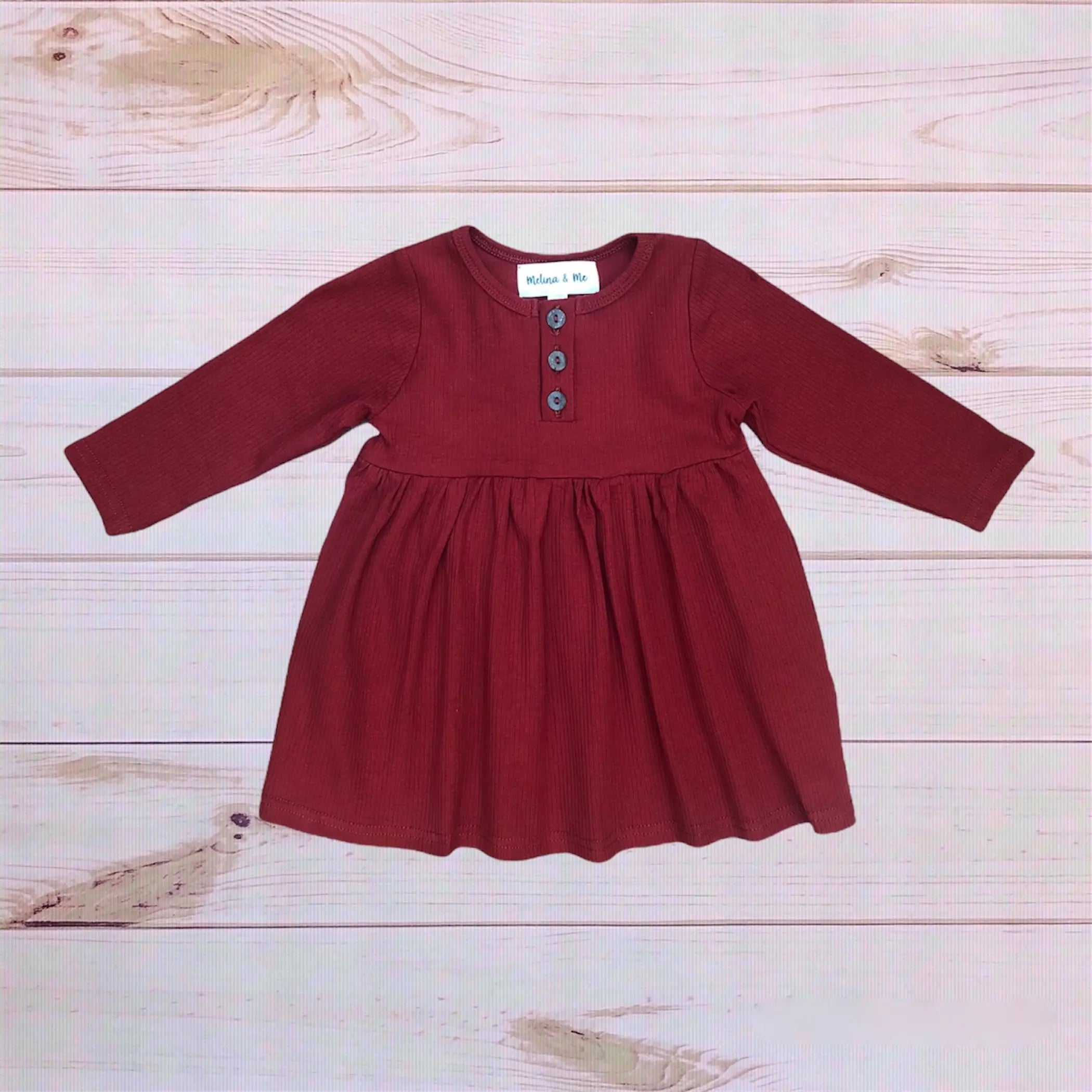 Rust ribbed long-sleeve dress with button detail and flared skirt for toddlers. Ideal for fall fashion.