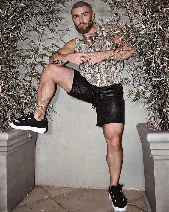 Men's snake print tank top, black faux leather shorts, and black sneakers, perfect for trendy summer streetwear.