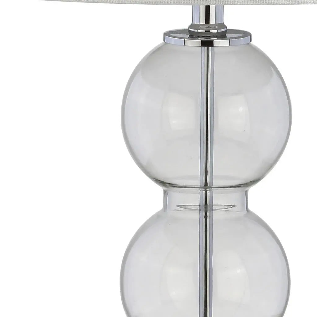 Clear glass table lamp with double globe design and chrome accents, featuring a stylish fabric shade.