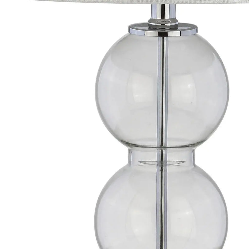 Clear glass table lamp with double globe design and chrome accents, featuring a stylish fabric shade.